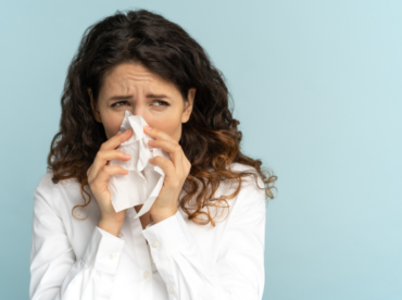 mulher assoando nariz ilustra artigo sobre como a rinite ataca os olhos